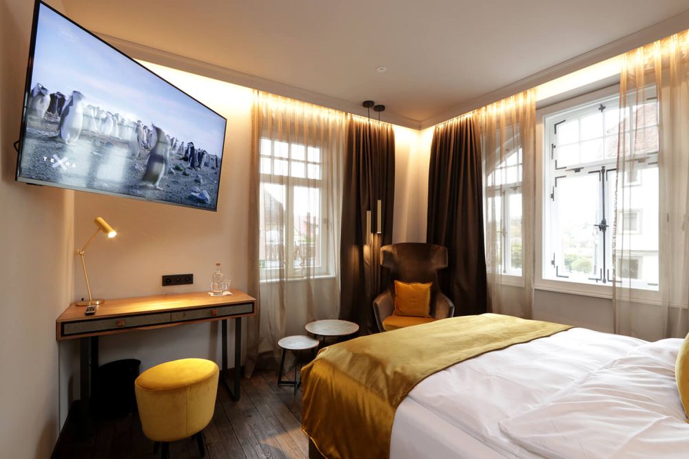 Blick auf den gemütlichen Sessel, den praktischen Tisch und den großen Smart TV des Zimmers 301
