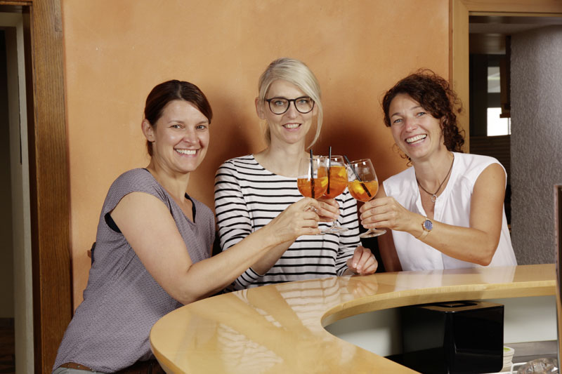 Drei Freundinnen stoßen mit Aperol an